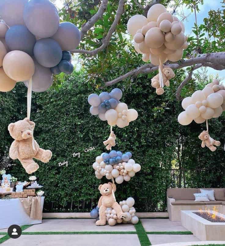 Colorful balloon decorations for baby shower party with teddy bears and cozy seating.