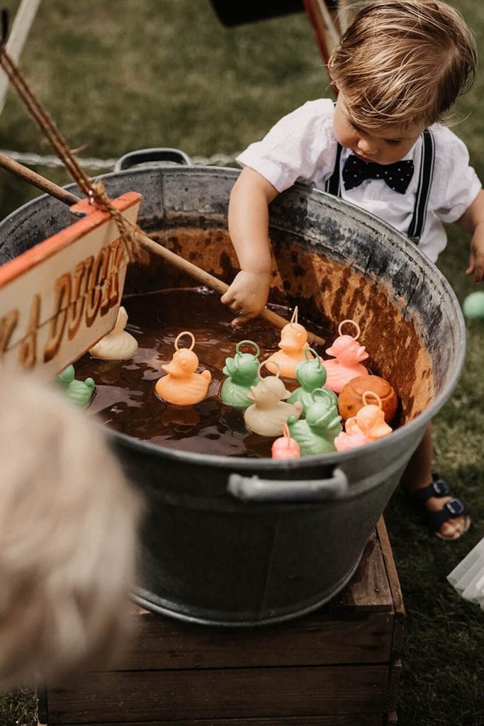 Colorful rubber duck game at outdoor event with children playing and enjoying carnival fun.