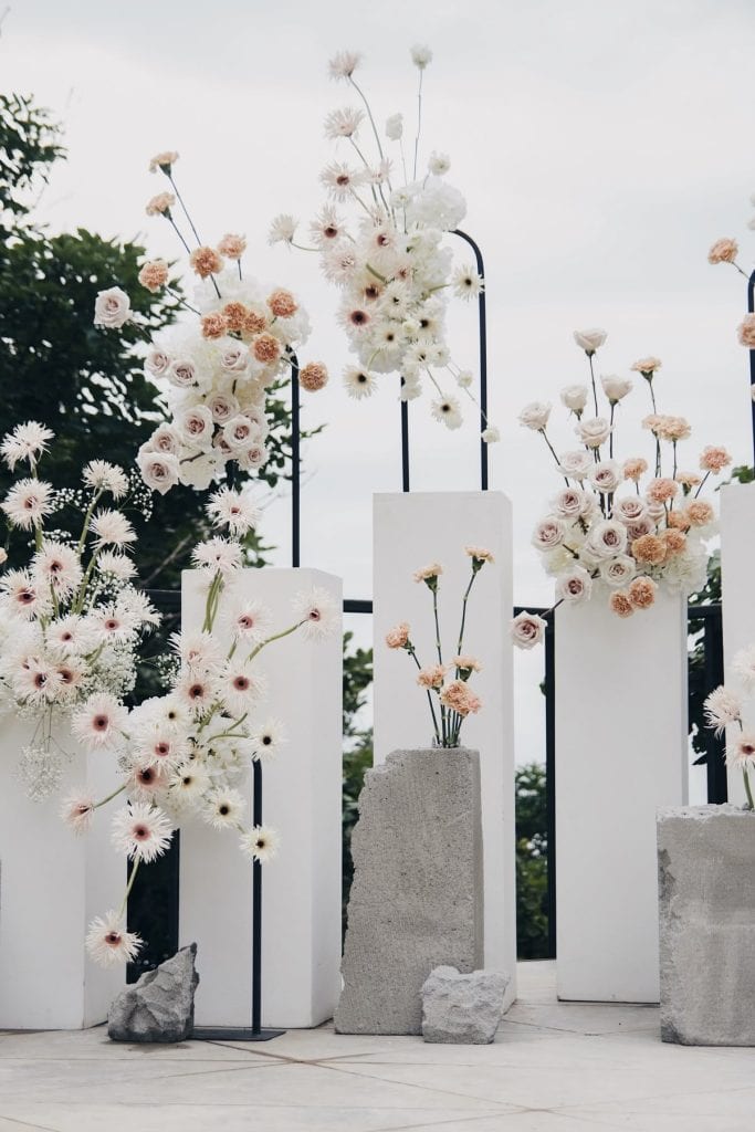 Elegant floral decor setup for UpEventi outdoor event with roses and daisies on white pedestals.